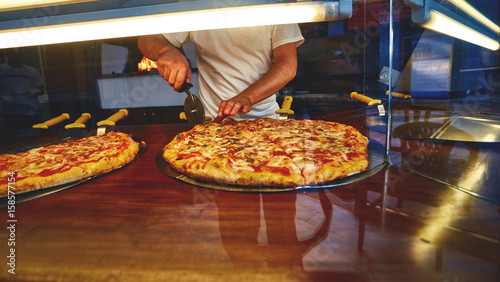 Food concept. Preparing traditional italian pizza. a man puts a fresh hot pizza on showcase in pizzeria. Ready to eat.