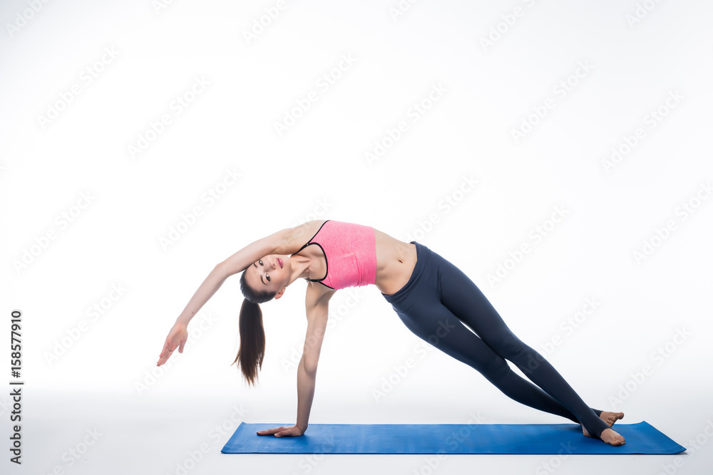 young woman yoga posing on isolated white studio background