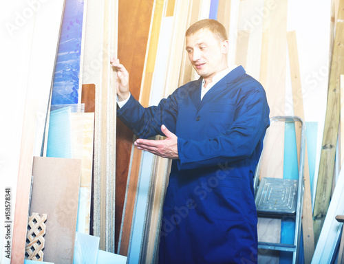portrait of man in uniform choosing compressed densified wood in photo