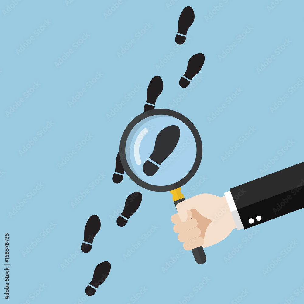 Hand holding magnifying glass over footsteps Hand holding magnifying glass over footsteps