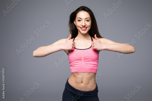 Beautiful fitness woman showing thumb up on white background