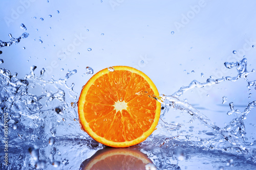 Juicy half an orange in splash of blue water