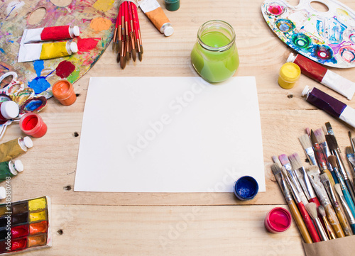 Paints, brushes and palette on the white wood background. The workplace of the artist. Banner for school