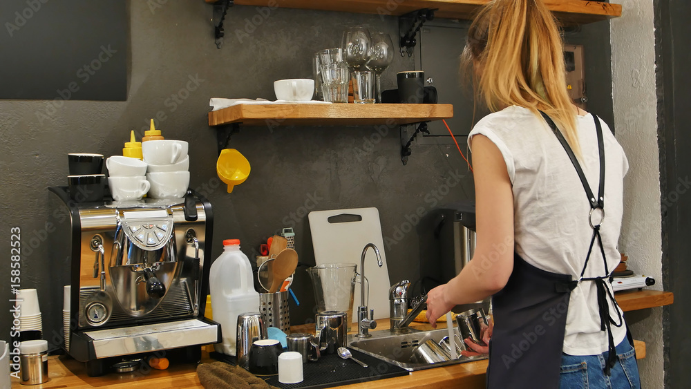Young female barista washing dishes at workplace Young female barista washing dishes at workplace
