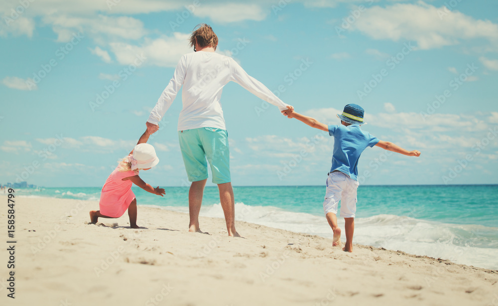 father with little son and daughter play at beach