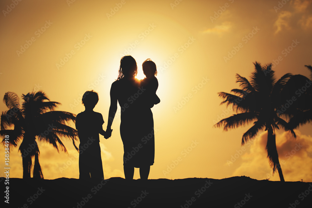 mother and two kids walking at sunset beach