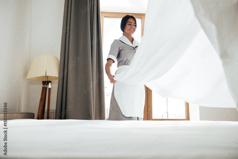 Hotel maid changing bed sheet - obrazy, fototapety, plakaty 