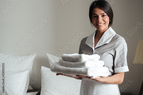 Portrait of a hotel maid holding fresh clean folded towels photo