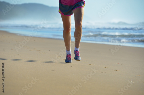 Fitness and running on beach, woman runner legs in shoes jogging on sand near sea, healthy lifestyle and sport concept 