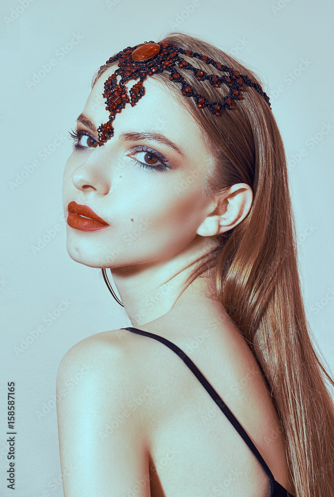 Woman with a beautiful face, makeup and jewelry in her hair. Portrait in a beauty salon. Clean skin. Red lipstick Woman with a beautiful face, makeup and jewelry in her hair. Portrait in a beauty salon. Clean skin. Red lipstick