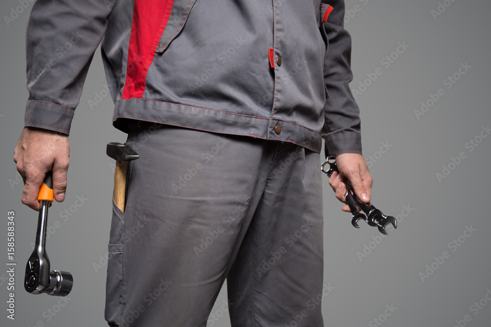 Serviceman holding tools in hands. Gray background. Serviceman holding tools in hands. Gray background.