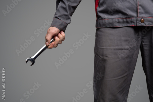 Serviceman holding wrench in hand. Gray background.