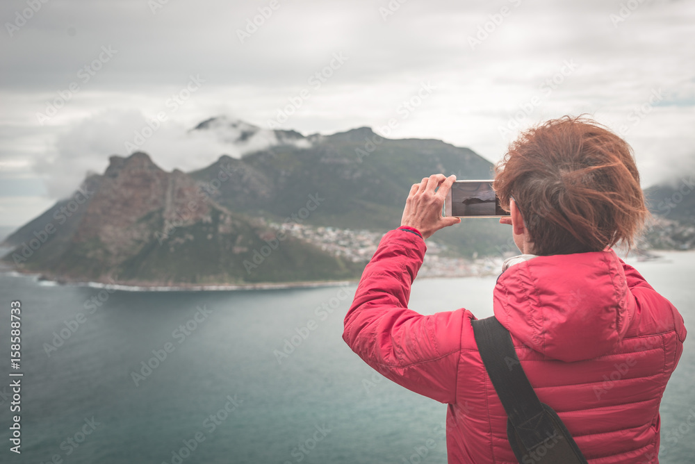 Φωτογραφία Tourist photographing with smart phone the landscape at Cape Town, on the atlantic coastline of South Africa