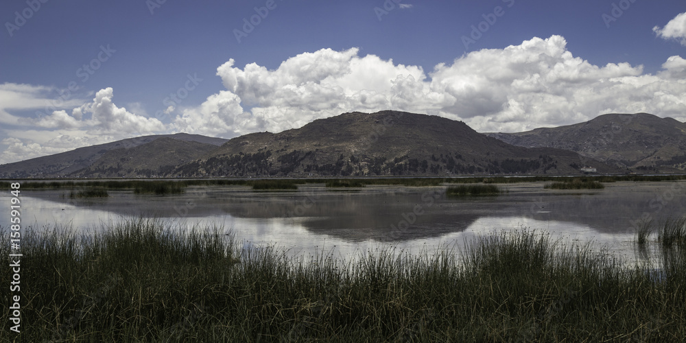 Reed, lake, mountains and clouds with reflection in the lake Titicaca, Peru