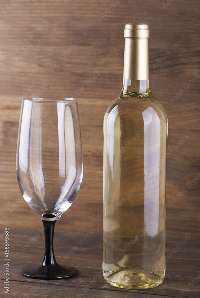 White wine bottle and a glass placed on wooden table. Copy space. Vertical studio shot