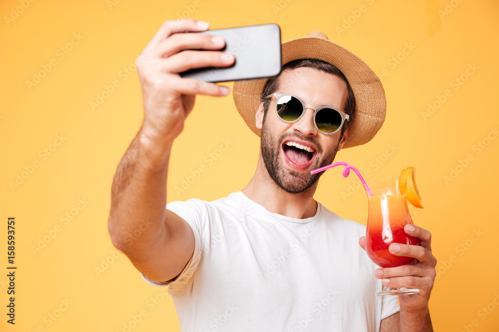 Smiling young man make selfie by phone holding cocktail. Smiling young man make selfie by phone holding cocktail.