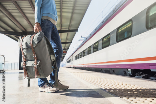 Young woman traveler waiting for a train on a railroad station, travel and active lifestyle concept