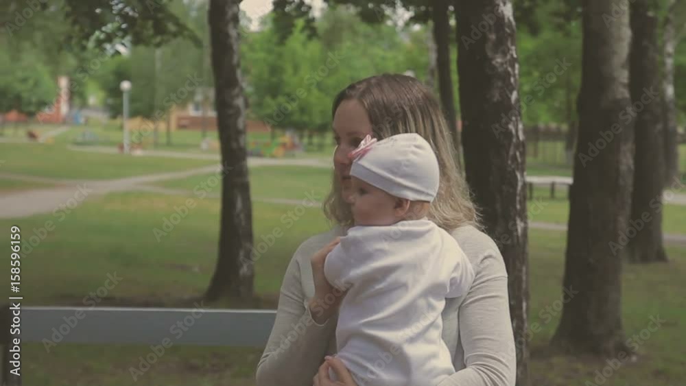 Beautiful woman walking with her little daughter and pushing stroller in park Beautiful woman walking with her little daughter and pushing stroller in park