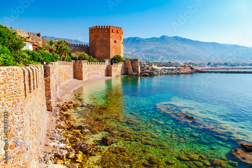 Kizil Kule tower in Alanya peninsula, Antalya district, Turkey, Asia. Famous tourist destination with high mountains. Part of ancient old Castle. Summer bright day photo