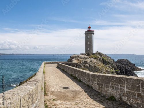 Ancient stone pier with lighthouse on the rocks overlooking the ocean