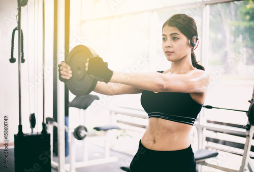 young fitness asian woman exercise with machine Cable Crossover and lifting dumbbells and barbells in gym for building muscles