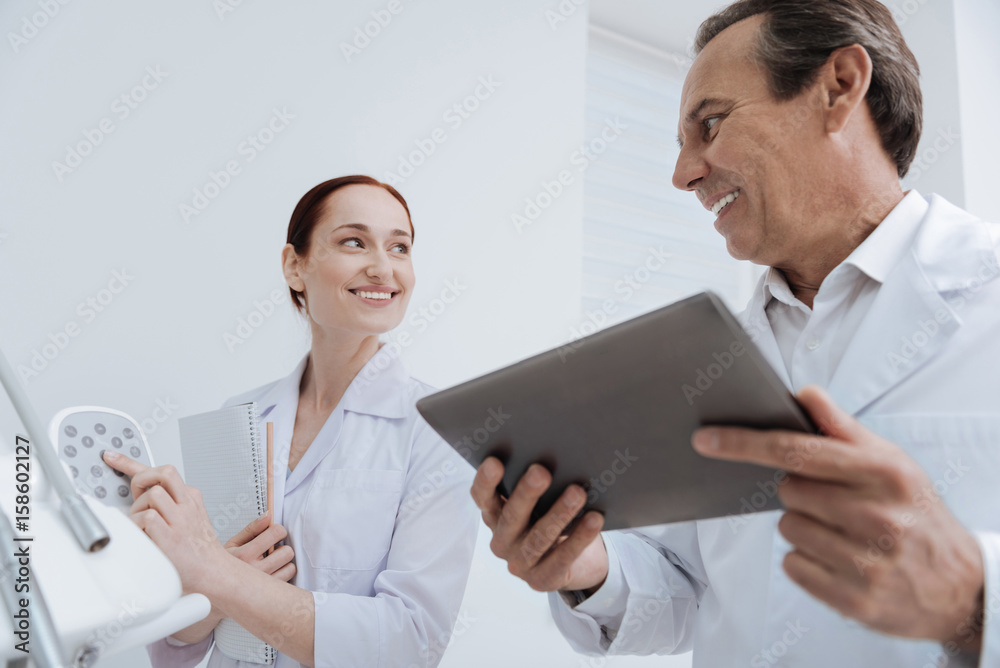 Happy doctor holding his gadget in both hands