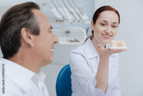 Smiling woman watching at artificial teeth
