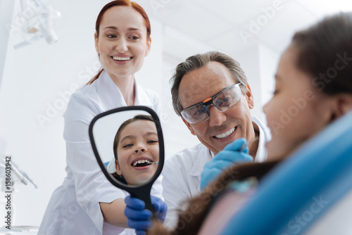 Smiling intern holding mirror in right hand