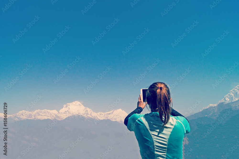 Girl takes pictures of mountains on a tablet.
