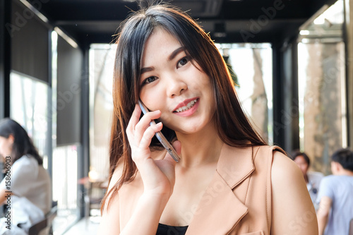 Business women in casual use cellphone for talking with customer in cafe