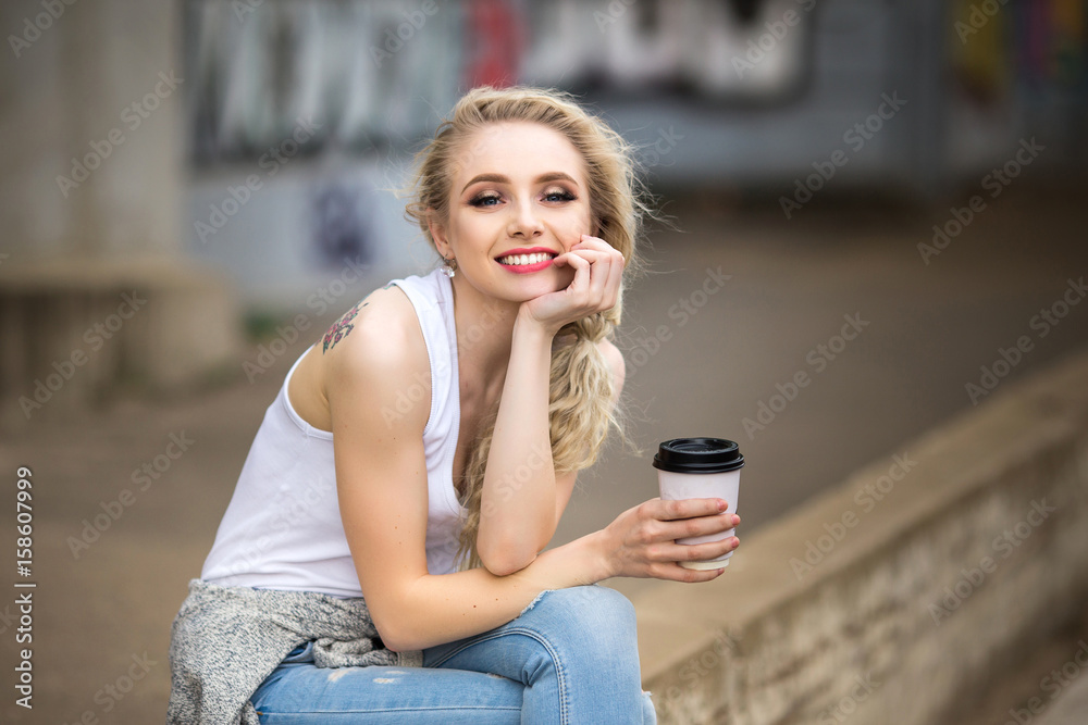 Beautiful girl drinks coffee on the street