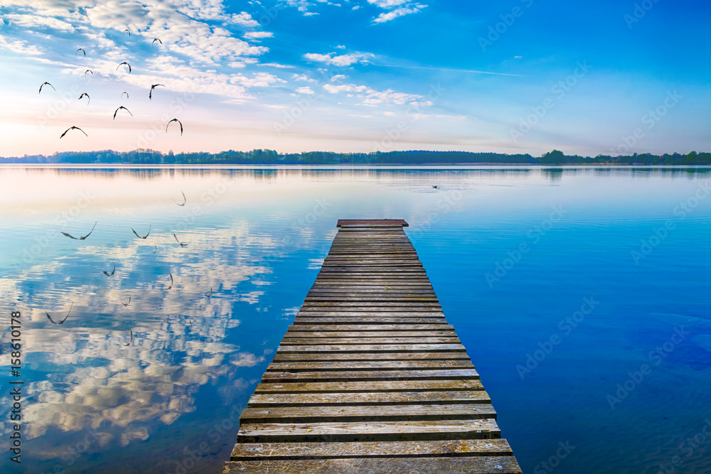 Fototapeta Dzikie ptaki przelatują nad pustą kładką. Jezioro Selment Wielki, Mazury, Polska.