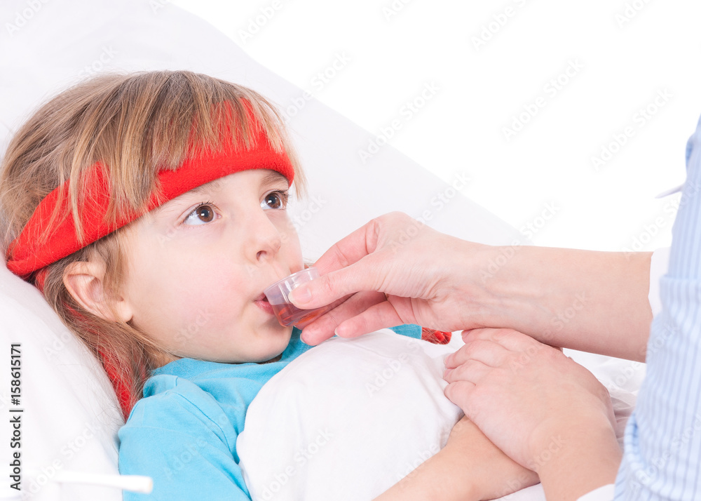 Mother giving her daughter cough syrup at home. Sick little girl in bed taking medicine with plastic cup. Mother giving her daughter cough syrup at home. Sick little girl in bed taking medicine with plastic cup.