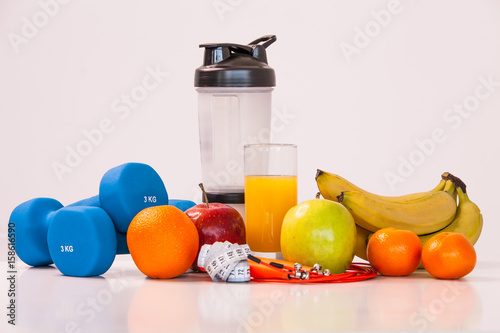 The concept of a healthy diet. Fintes meals. Sport lifestyle. Dumbbells. Shaker. Oranges. Apples. Bananas. fruit juice. The skipping rope. Measuring tape waist. on a white background. studio shooting.