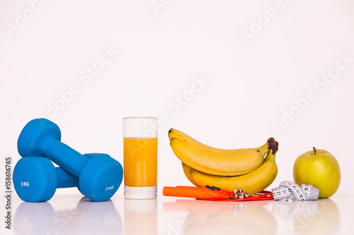 The concept of a healthy diet. Fintes meals. Sport lifestyle. Dumbbells. green apple. Bananas. The skipping rope. Measuring tape waist. on a white background