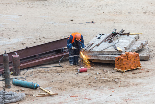 Welder working at construction site. Worker in helmet welds a metal bar