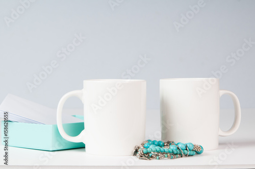 mockup of two white coffee mugs in a simple setting