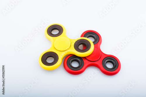 Red and yellow fidget finger spinner stress anxiety relief toy isolated on white background.