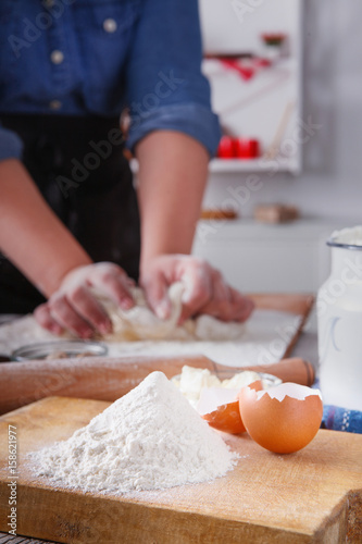 Woman baker knead yeast dough with eggs and flour