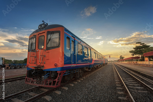 Beautiful railway station with modern red commuter train at colorful sunset in , Railroad with vintage toning