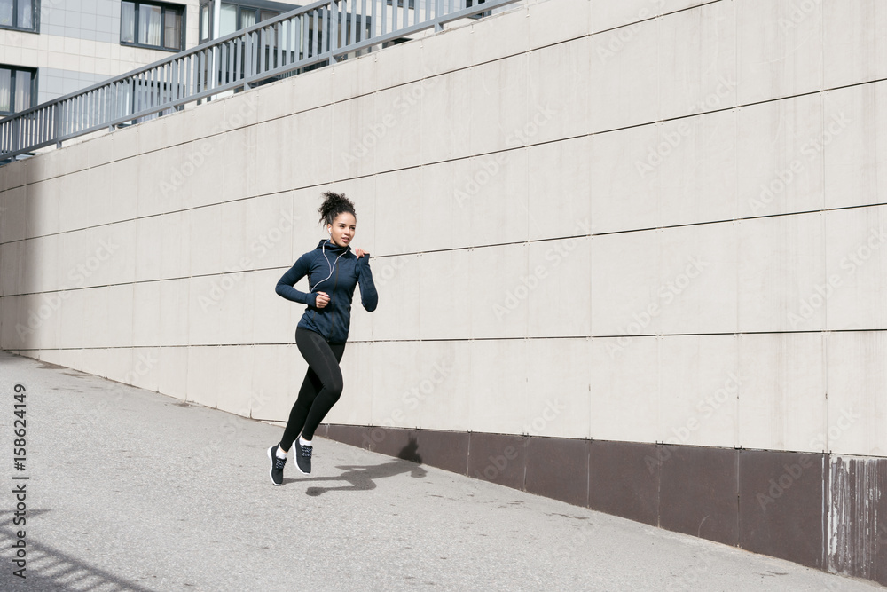 Mixed race woman wearing sports clothes, running on city street
