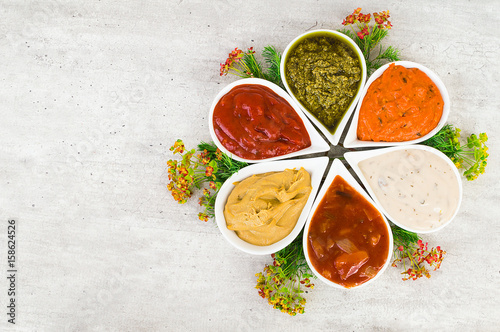 A set of sauces in a form of flower on a light gray stone background.