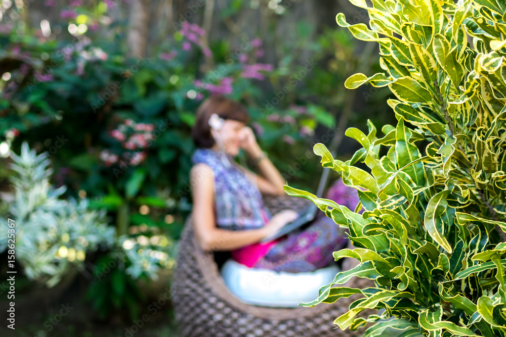 Obraz premium Young beautiful woman working with laptop at outdoor tropical park, smile and happy relaxing feeling in the morning, freelancer working businesswoman lifestyle concept. Bali island, Indonesia.