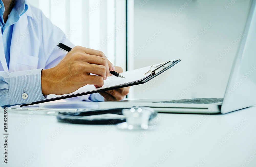 Stethoscope with clipboard and Laptop on desk, Doctor working in hospital writing a prescription, Healthcare and medical concept, test results in background, vintage color, selective focus. Stethoscope with clipboard and Laptop on desk, Doctor working in hospital writing a prescription, Healthcare and medical concept, test results in background, vintage color, selective focus.