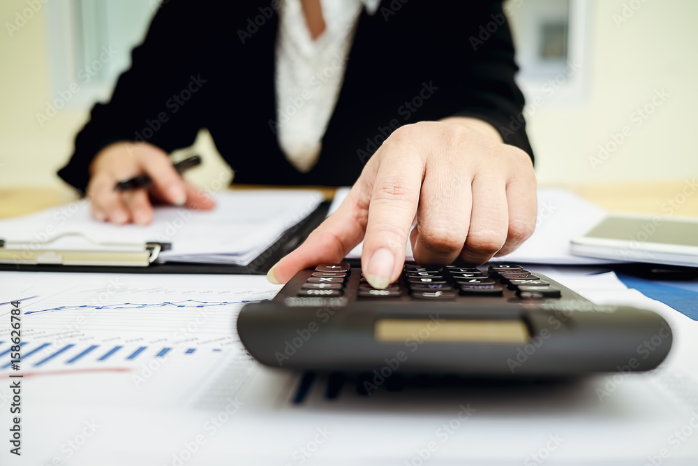 Close up young Asian Business woman using a calculator to calculate the numbers.Business finances and accounting concept Close up young Asian Business woman using a calculator to calculate the numbers.Business finances and accounting concept