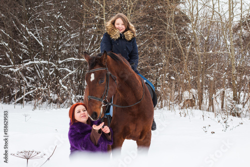 Teenager girl, mom and horse in a winter