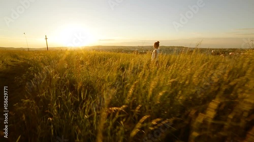 Young girl walking on the field to cross on sunset