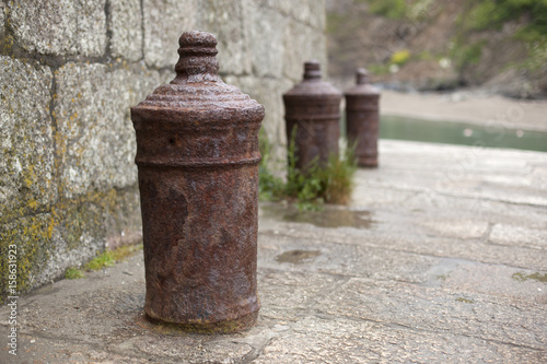 Old rusty mooring posts at Polkerris harbour, Cornwall photo