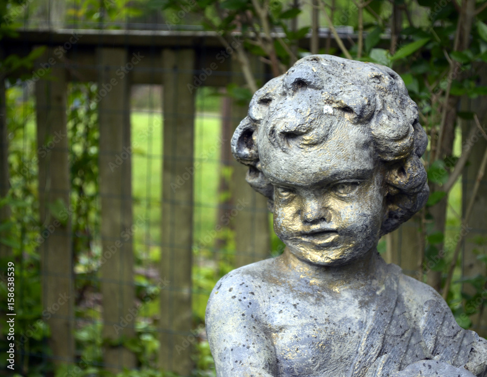 Stone cherub statue in garden 