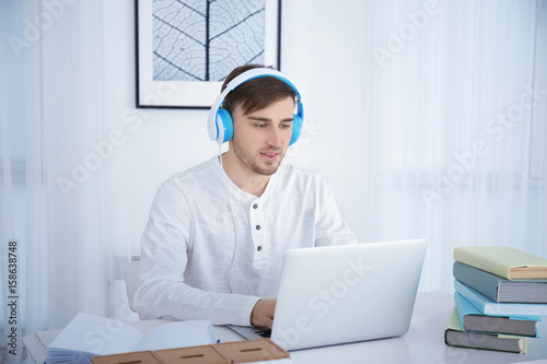 Young man in headphones usi...